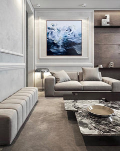 Original art painting with gestural brushstrokes inspired by the waves in the ocean and wind in the trees in a predominantly blue and green colour palette on a white background. The painting is framed in sustainably sourced raw American Ash similar in look to Tasmanian oak. The painting in the image is featured in a contemporary interior designed lounge room/sitting area.